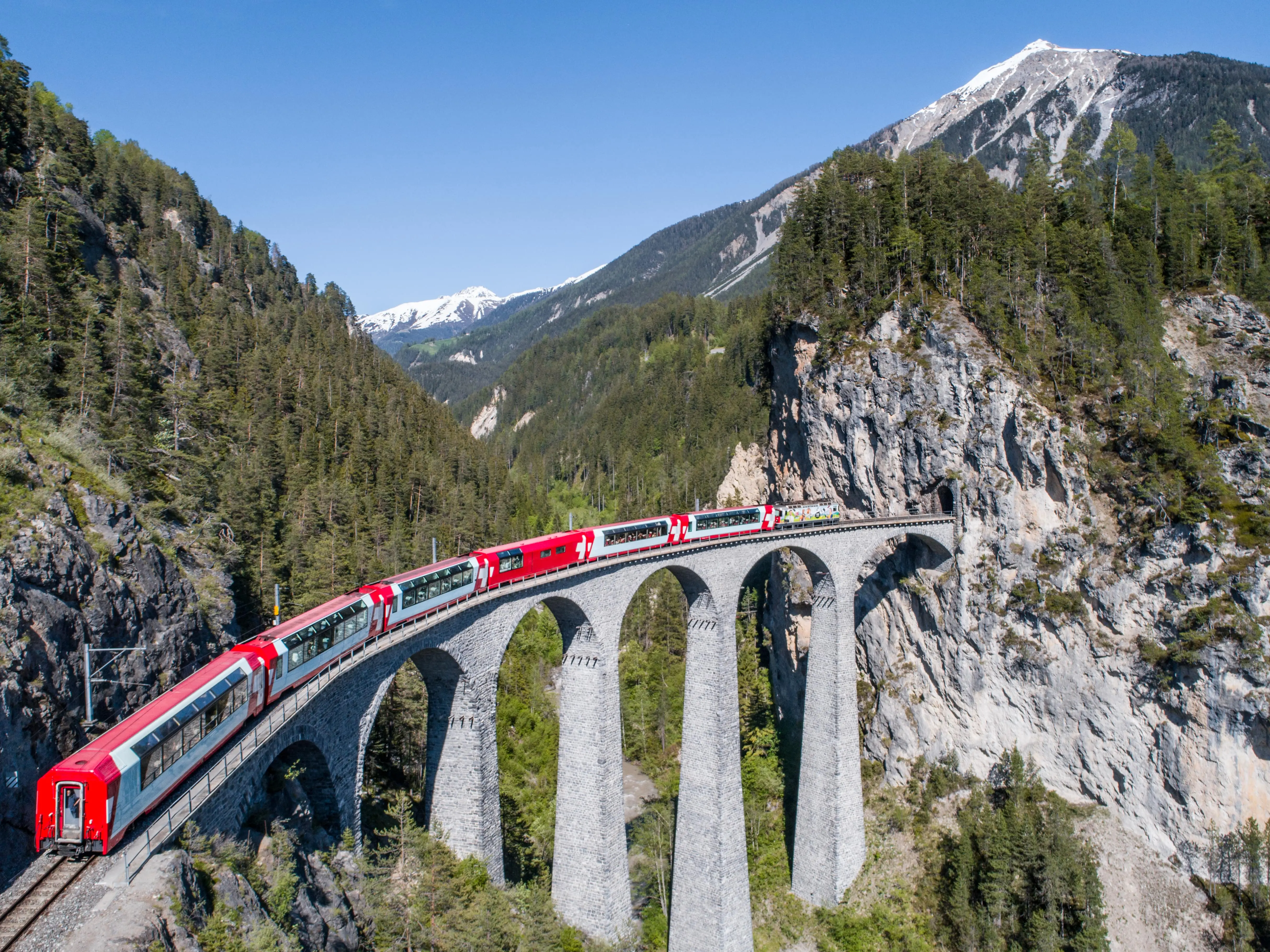 Travelling by Train: A red Bernina Express train in the mountains