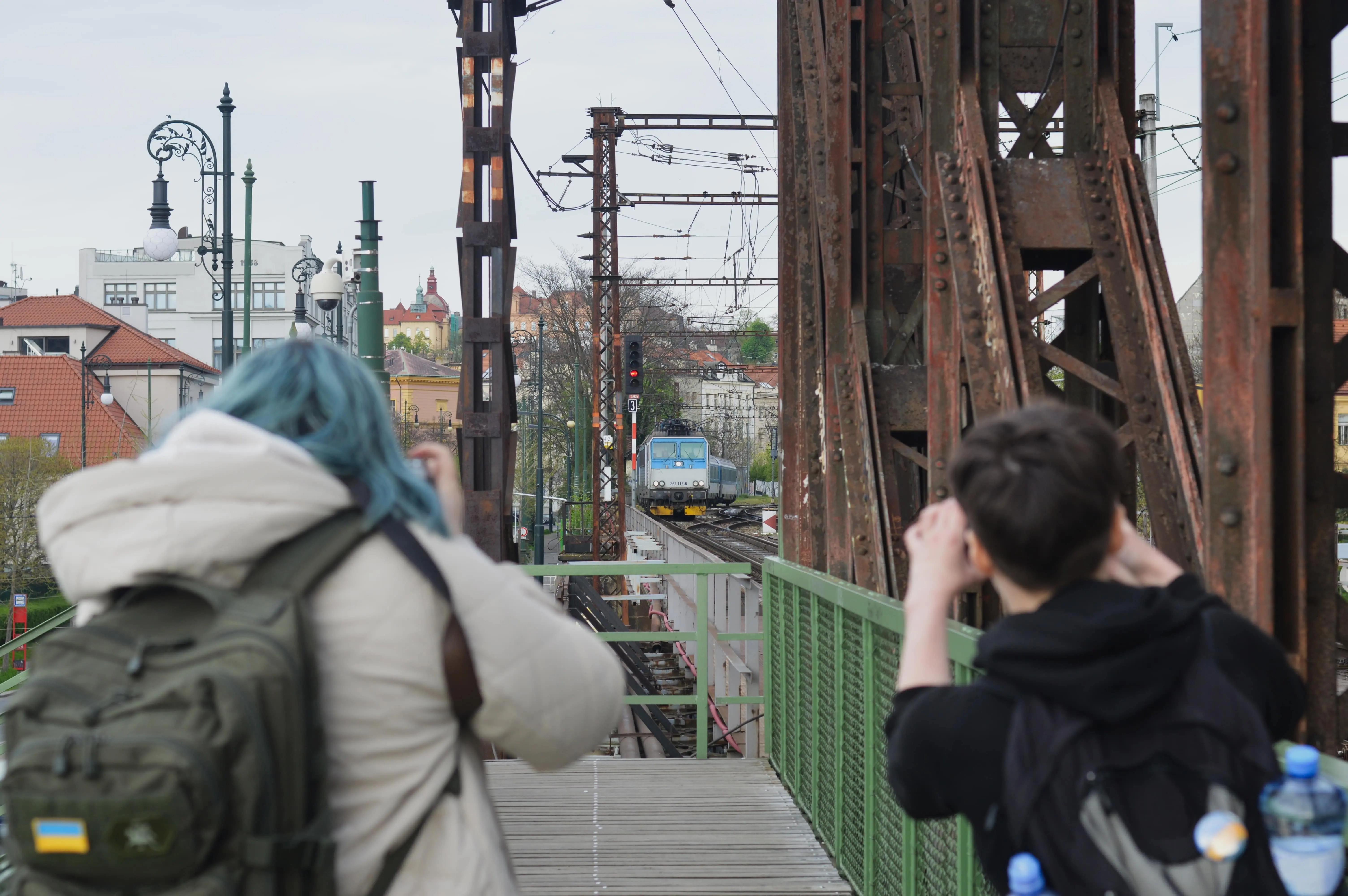 Famous Train Spotters: Two women spotting a train in a dense urban setting.