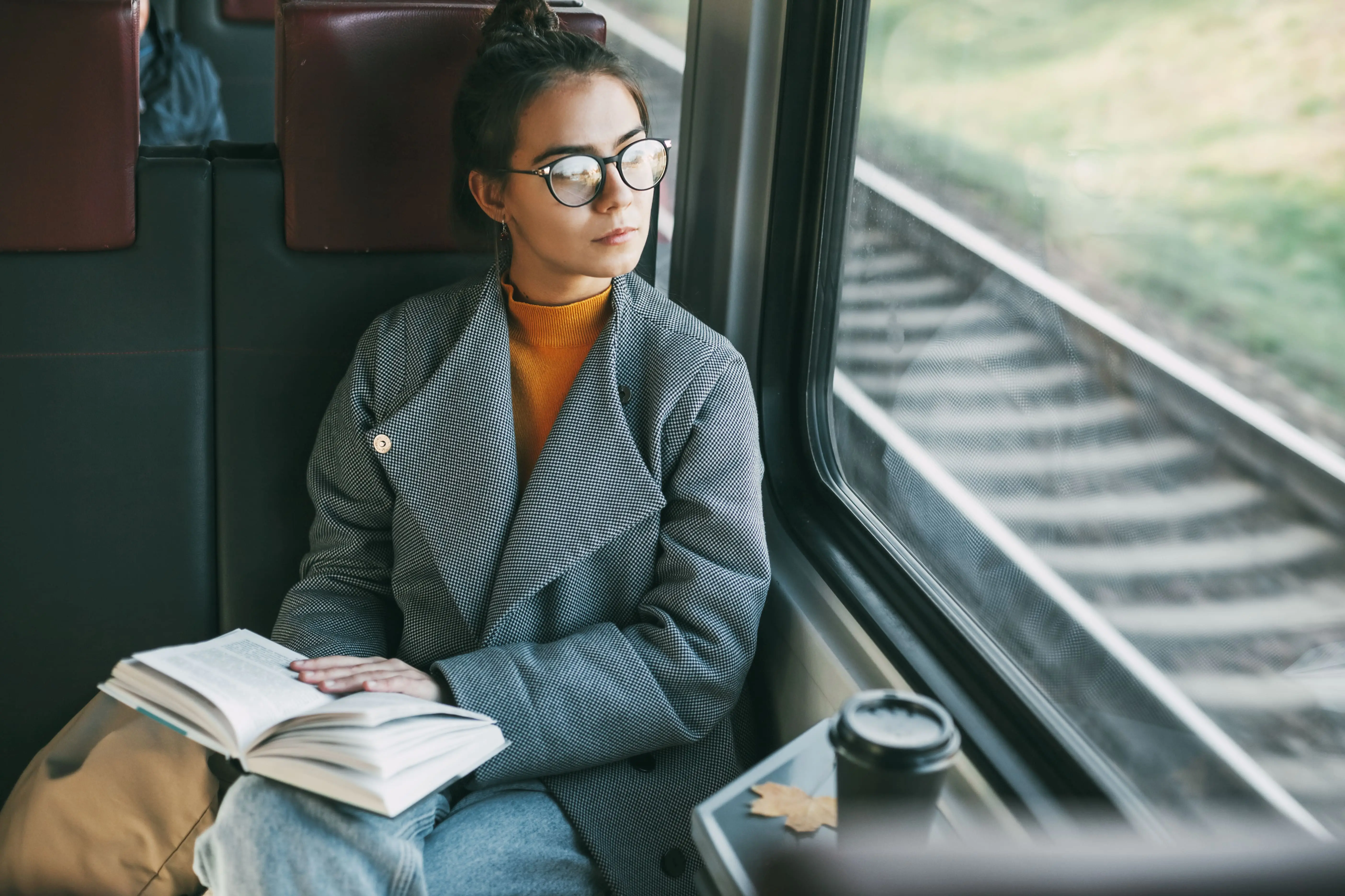 Train Books: A young woman sits on a train, looking out of the window whilst reading a book.