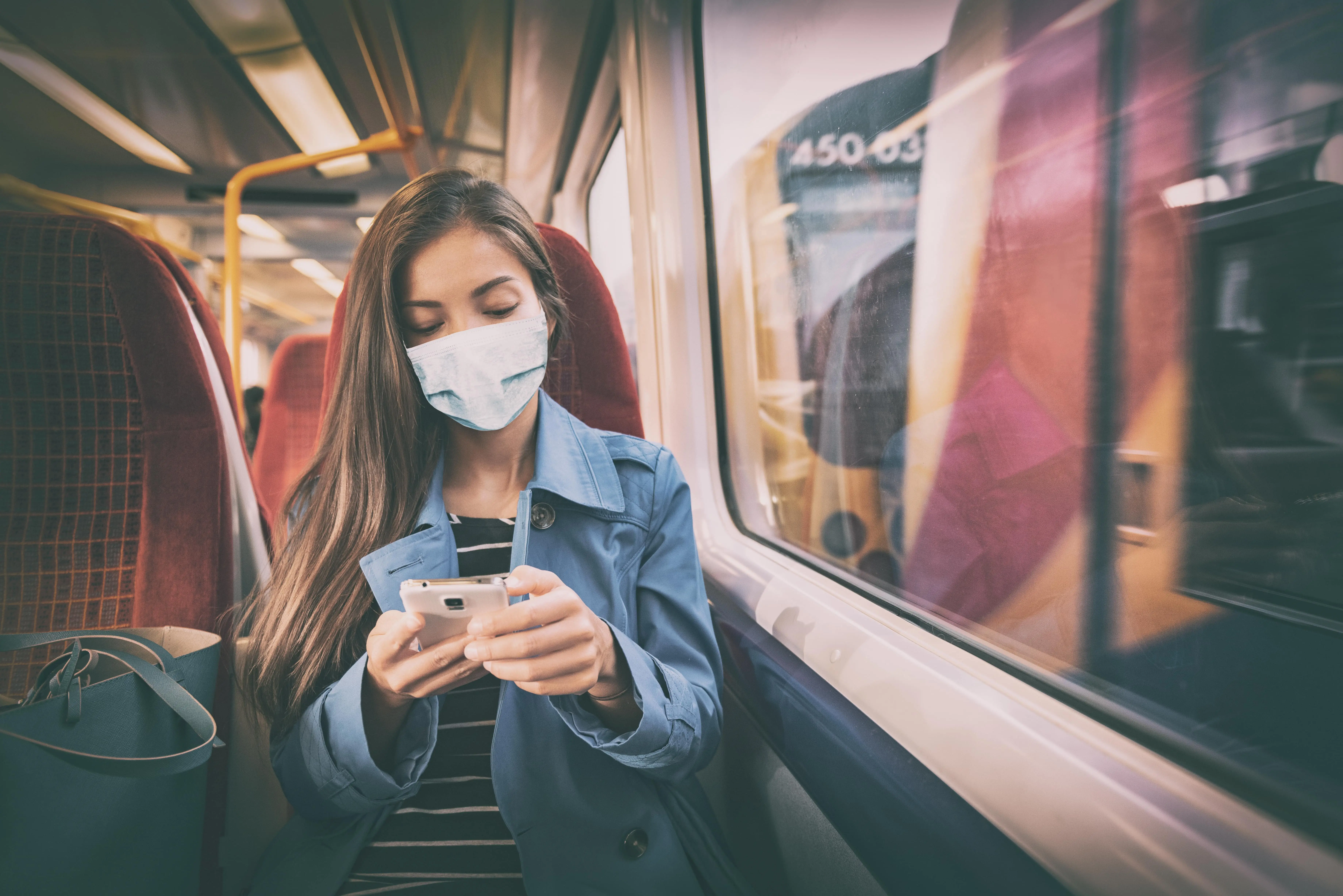 The World’s Most Iconic Trains: A woman travelling on a train wearing a facemask.