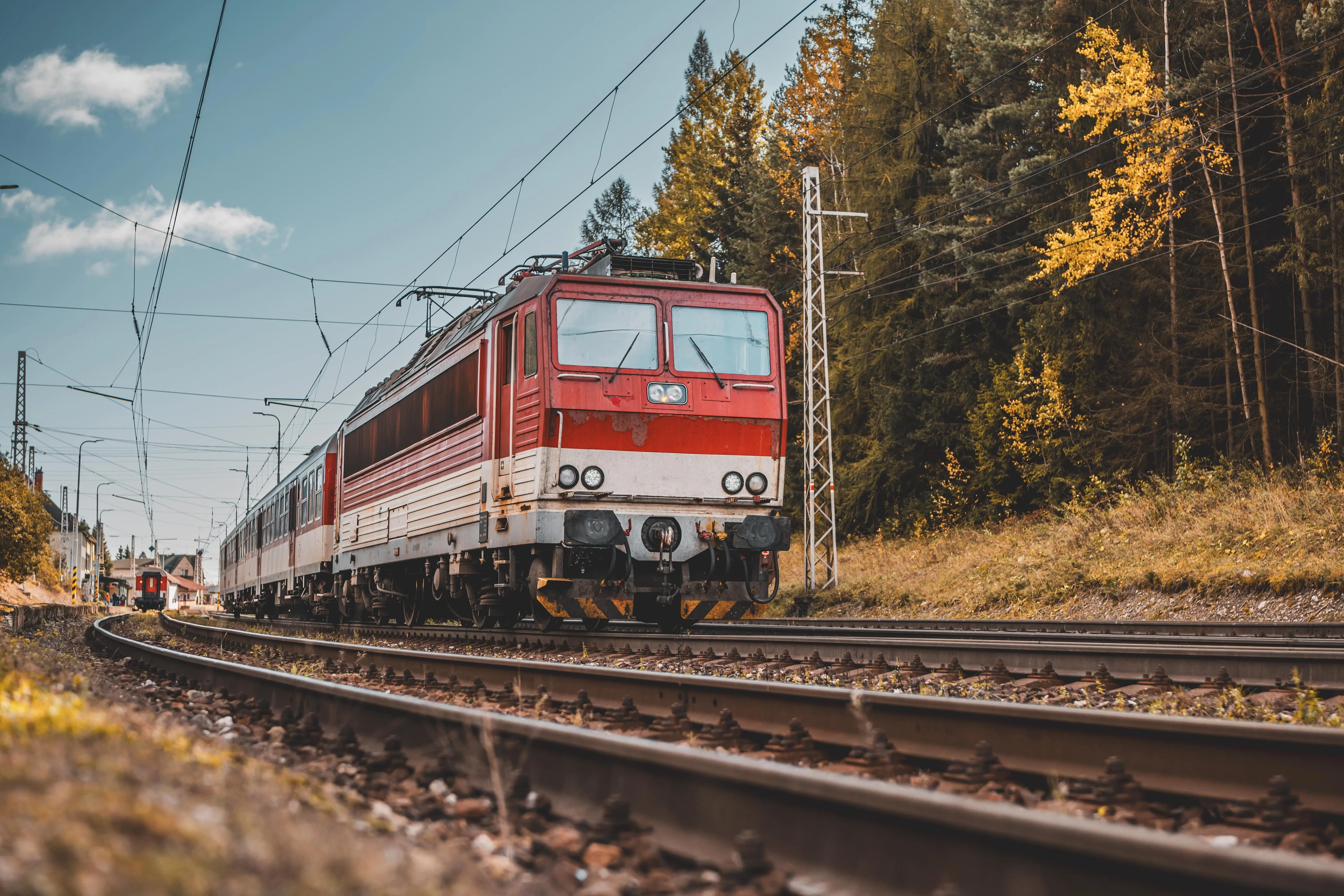 An old passenger train travels over rails during autumn
